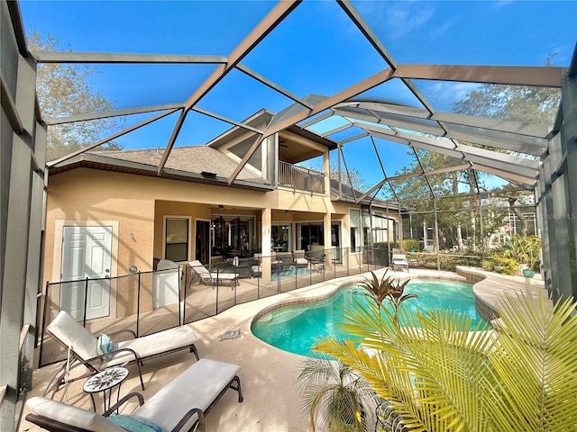 pool with glass enclosure, a ceiling fan, and a patio