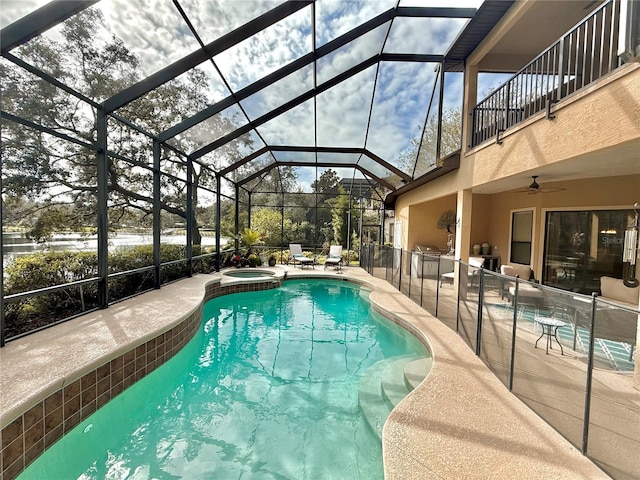 view of pool with a ceiling fan, a pool with connected hot tub, glass enclosure, and a patio