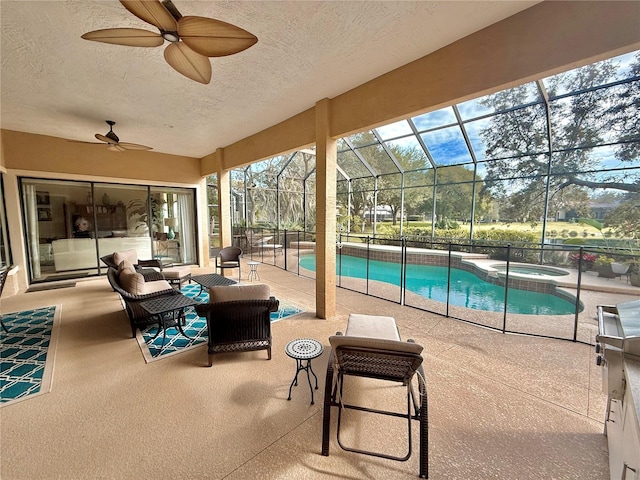 view of pool featuring a pool with connected hot tub, a patio area, ceiling fan, and glass enclosure