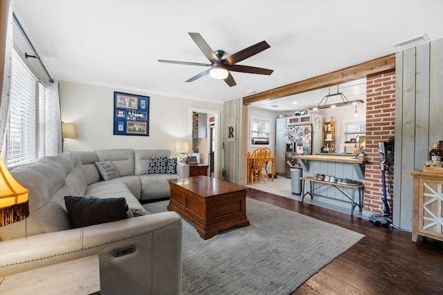 living room with a ceiling fan, visible vents, and wood finished floors