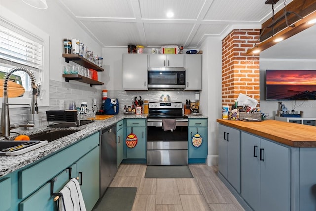 kitchen with a sink, appliances with stainless steel finishes, backsplash, wood tiled floor, and open shelves