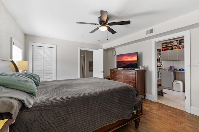 bedroom featuring a closet, wood finished floors, visible vents, and a ceiling fan