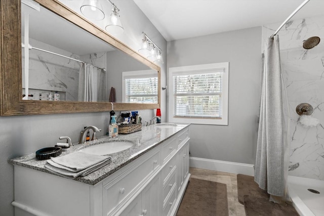 full bathroom with a sink, a shower stall, baseboards, and double vanity