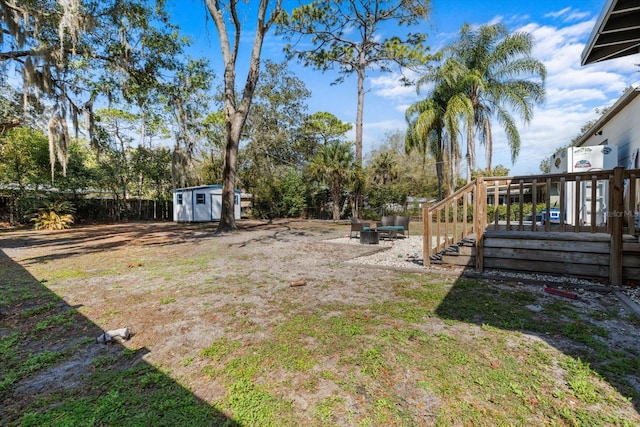 view of yard featuring a shed, a wooden deck, a fenced backyard, and an outbuilding