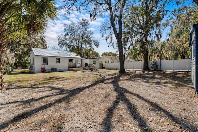 back of property featuring a fenced backyard, metal roof, and central AC unit