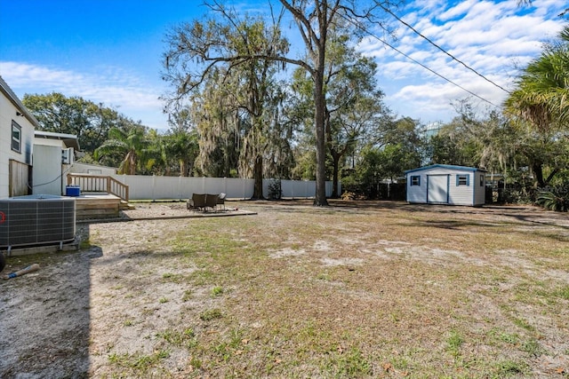 view of yard featuring an outbuilding, a storage shed, central AC unit, and fence