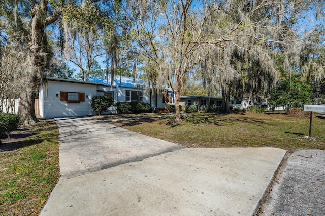 view of front of home featuring a front yard, concrete block siding, and driveway