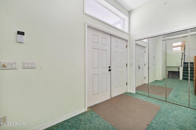 carpeted foyer entrance featuring stairs, a high ceiling, and baseboards