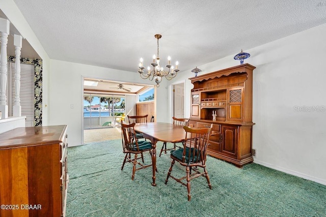 dining area featuring a textured ceiling, baseboards, carpet flooring, and ceiling fan with notable chandelier