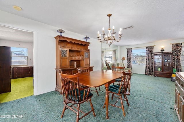 carpeted dining room with a textured ceiling, baseboards, visible vents, and a notable chandelier