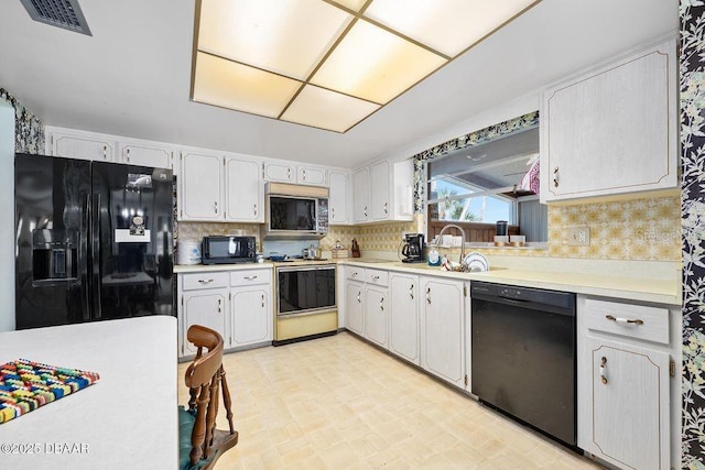 kitchen featuring black appliances, visible vents, light countertops, and decorative backsplash