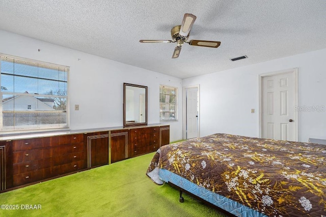 carpeted bedroom featuring a textured ceiling, visible vents, and a ceiling fan