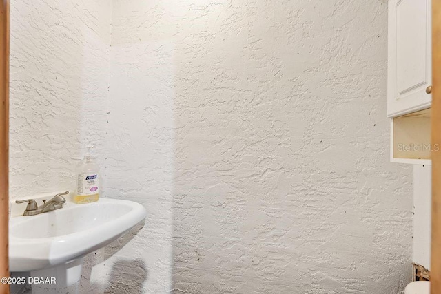 bathroom featuring a textured wall and a sink