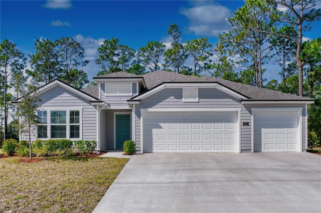 view of front of property featuring a garage, concrete driveway, a front lawn, and roof with shingles