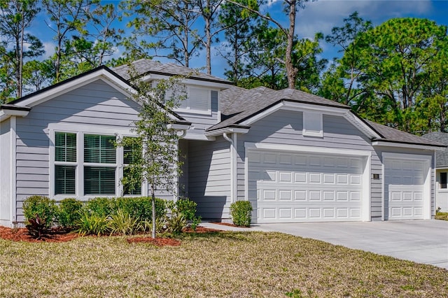 view of front of property featuring a garage, a front yard, concrete driveway, and a shingled roof