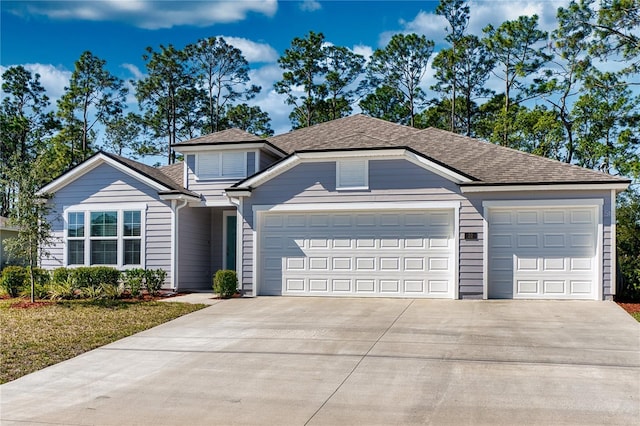 view of front facade featuring a garage, driveway, and a shingled roof