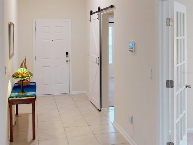 hallway featuring light tile patterned floors, baseboards, and a barn door