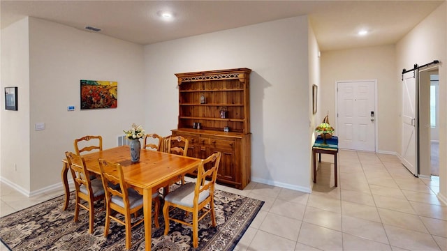 dining space featuring light tile patterned floors, a barn door, visible vents, and baseboards