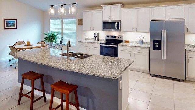 kitchen with light tile patterned floors, a breakfast bar area, stainless steel appliances, a sink, and white cabinets