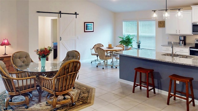 dining area with lofted ceiling, light tile patterned flooring, baseboards, and a barn door