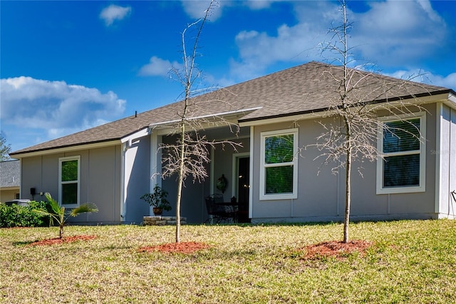 back of house with roof with shingles and a yard