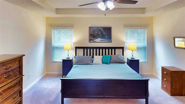 bedroom with light carpet, multiple windows, and a raised ceiling