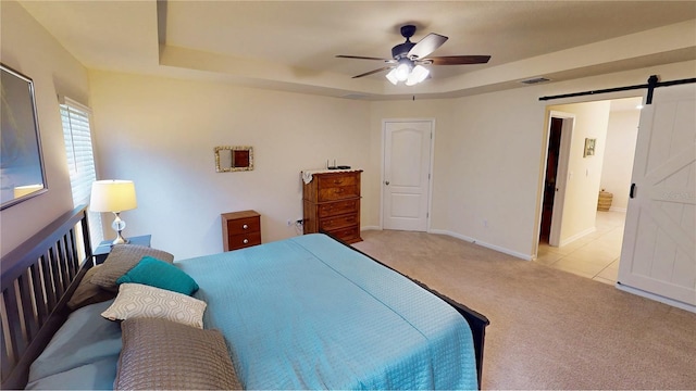 bedroom with carpet, a barn door, visible vents, and a raised ceiling