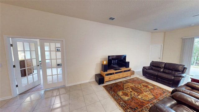 living room with french doors, visible vents, light tile patterned flooring, a textured ceiling, and baseboards