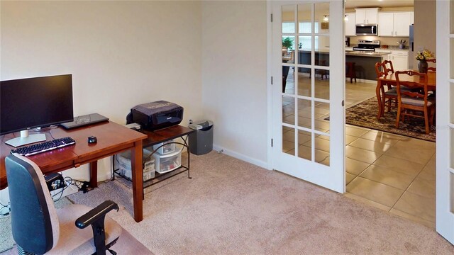 home office with light tile patterned floors, baseboards, and light colored carpet