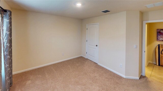 carpeted spare room featuring baseboards and visible vents