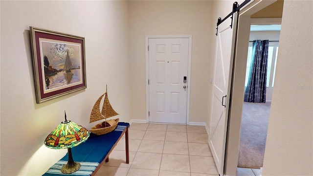 foyer featuring light tile patterned floors, a barn door, and baseboards