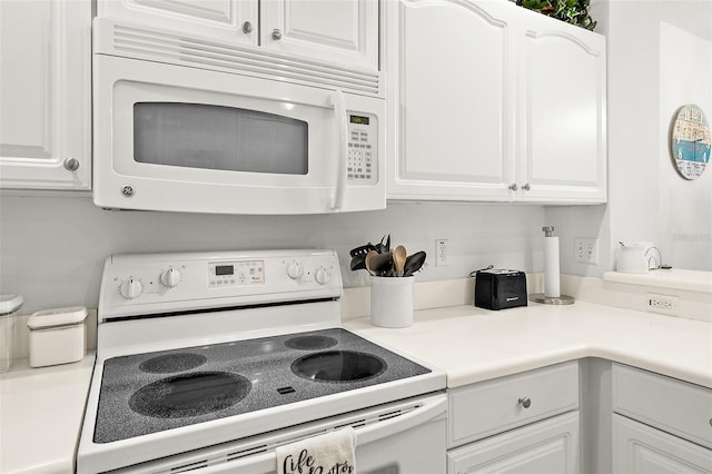 kitchen featuring light countertops, white appliances, and white cabinetry