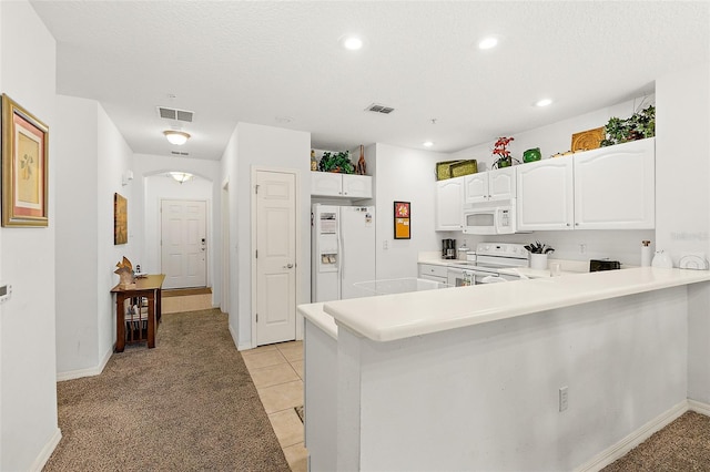 kitchen featuring arched walkways, white appliances, visible vents, and white cabinetry