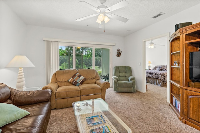 carpeted living area with a textured ceiling, visible vents, and a ceiling fan