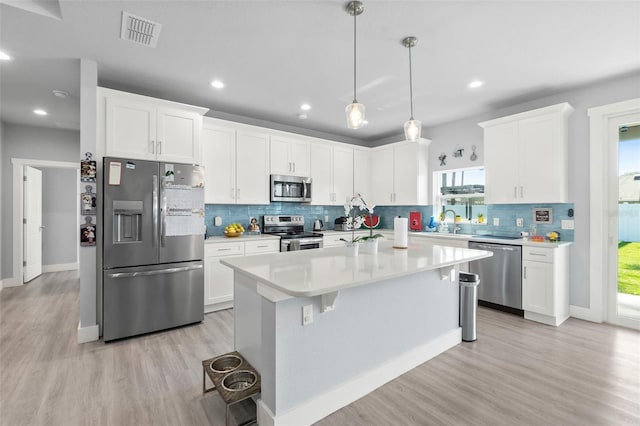 kitchen featuring stainless steel appliances, light countertops, visible vents, white cabinetry, and a sink