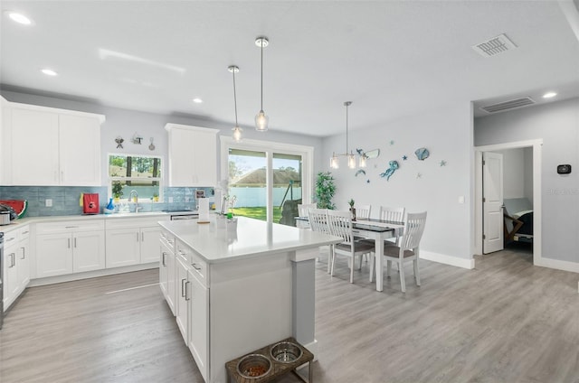 kitchen featuring light countertops, tasteful backsplash, light wood-style flooring, and visible vents