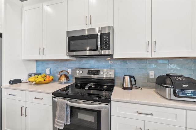 kitchen featuring stainless steel appliances, white cabinets, and tasteful backsplash