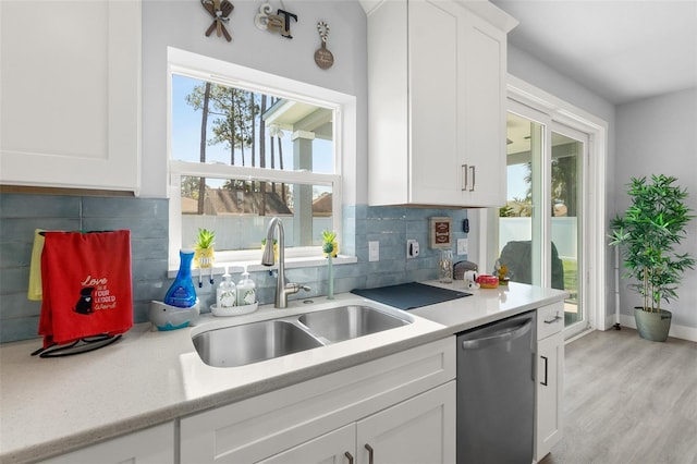 kitchen with dishwasher, light countertops, a sink, and white cabinetry