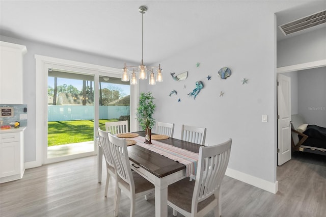 dining space with light wood-style flooring, visible vents, and baseboards