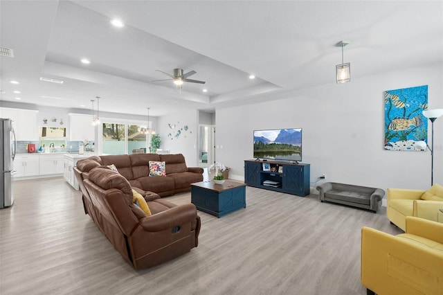 living area featuring light wood finished floors, visible vents, a tray ceiling, and recessed lighting