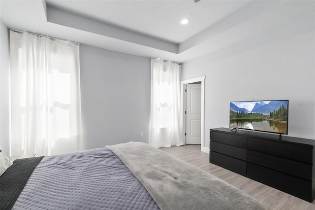 bedroom featuring a tray ceiling, recessed lighting, and wood finished floors