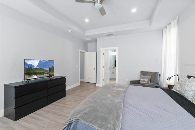 bedroom featuring a tray ceiling, recessed lighting, visible vents, light wood-style floors, and baseboards