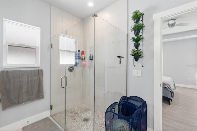 bathroom featuring ceiling fan, a stall shower, ensuite bath, and baseboards