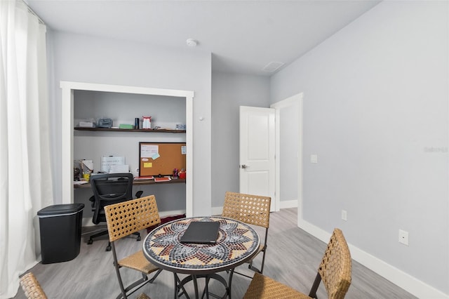 dining space with light wood-style flooring, visible vents, and baseboards