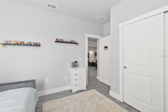 bedroom with wood finished floors, visible vents, and baseboards