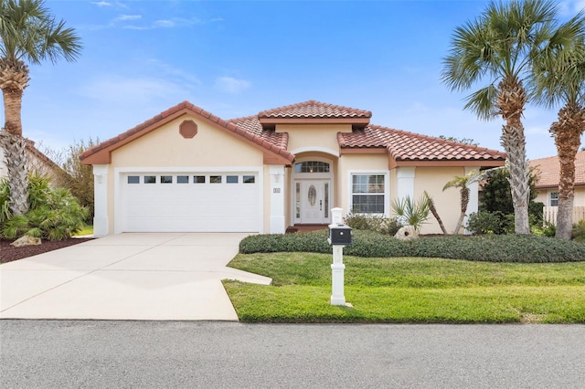 mediterranean / spanish house with a tile roof, stucco siding, concrete driveway, an attached garage, and a front lawn