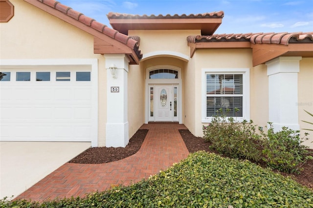 view of exterior entry featuring an attached garage and stucco siding