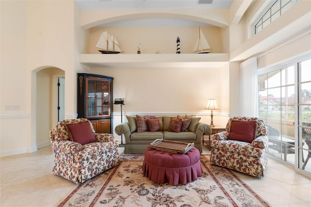 living area featuring baseboards, visible vents, a high ceiling, and tile patterned floors