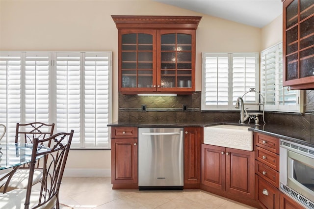 kitchen with vaulted ceiling, appliances with stainless steel finishes, backsplash, and a sink