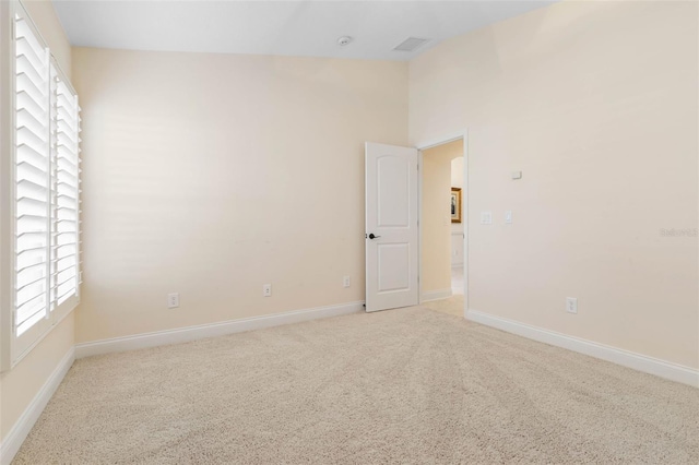 empty room featuring light carpet, visible vents, and baseboards